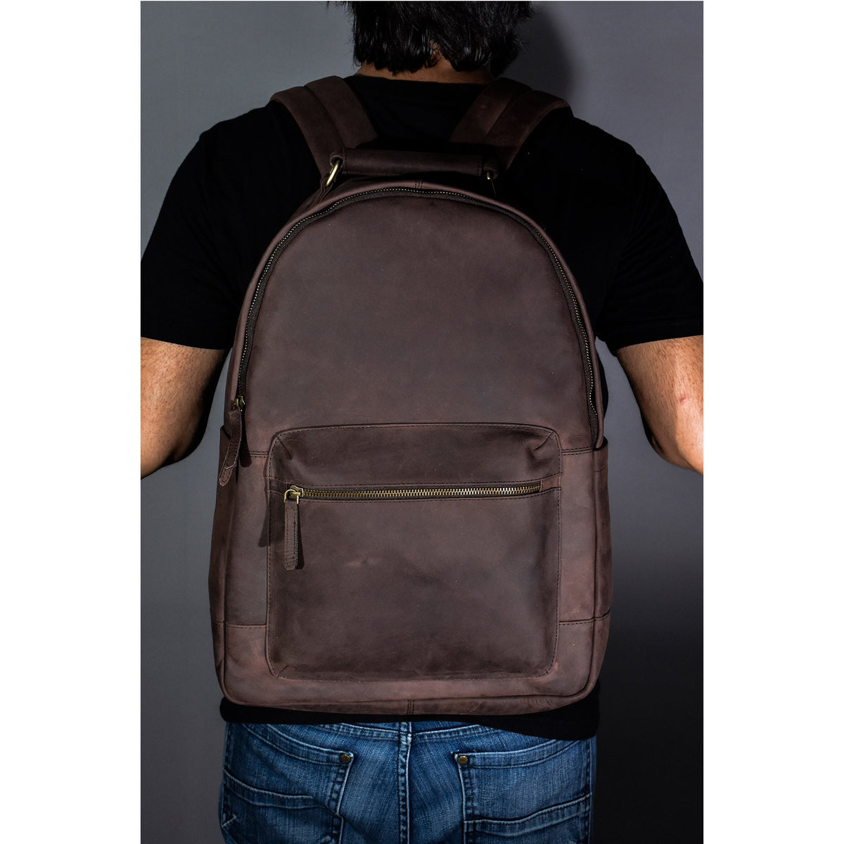 May include: A brown leather backpack with a zippered front pocket and adjustable straps.