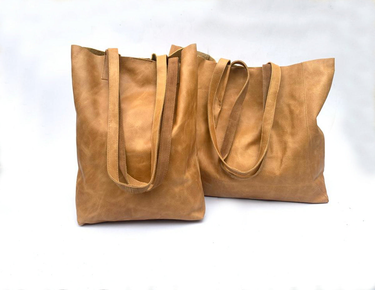 May include: Two brown leather tote bags with double straps. The bags are made of a soft, supple leather and have a casual, relaxed look.