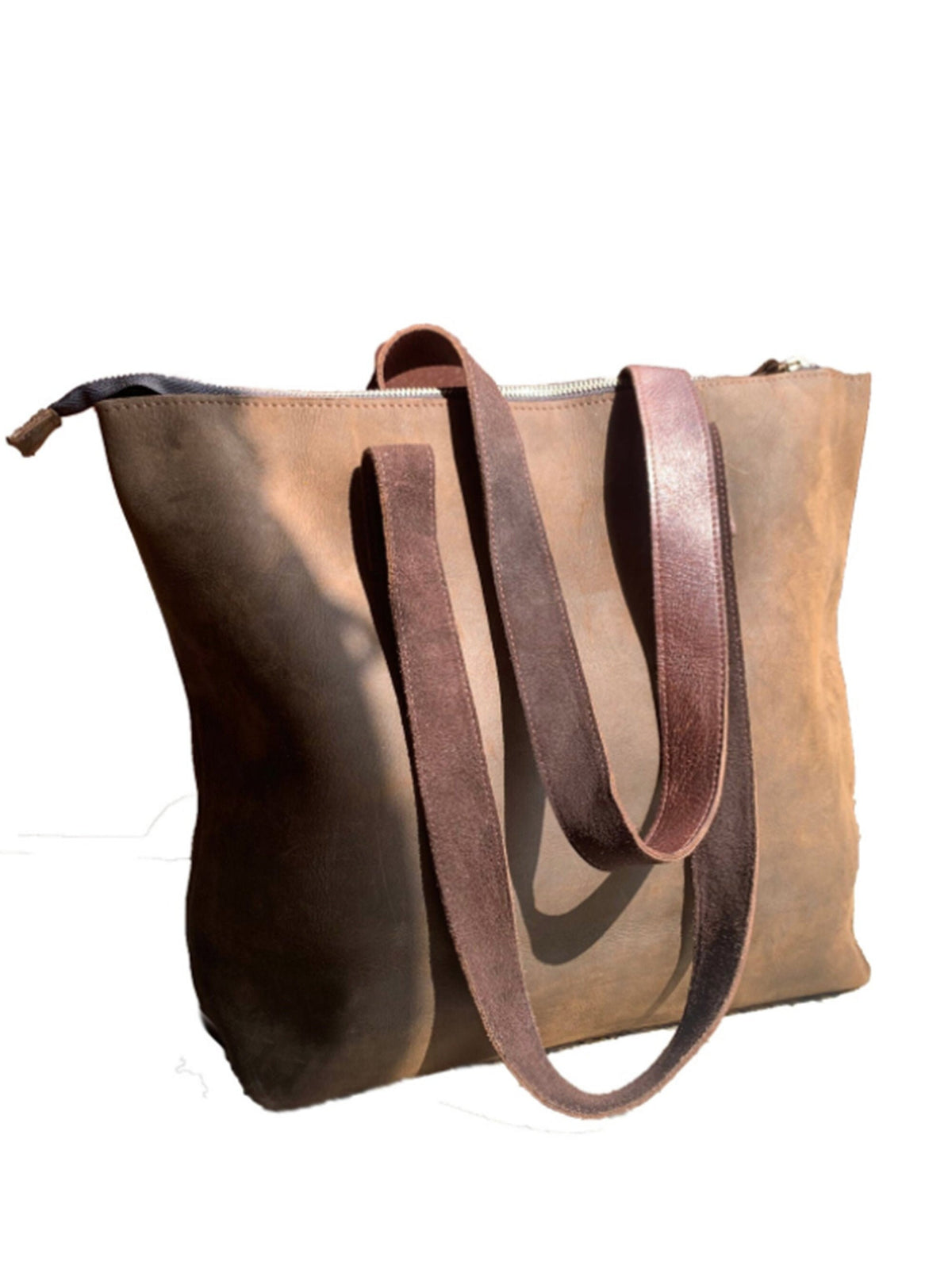 May include: A brown leather tote bag with brown leather straps. The bag has a zipper closure and a distressed look.