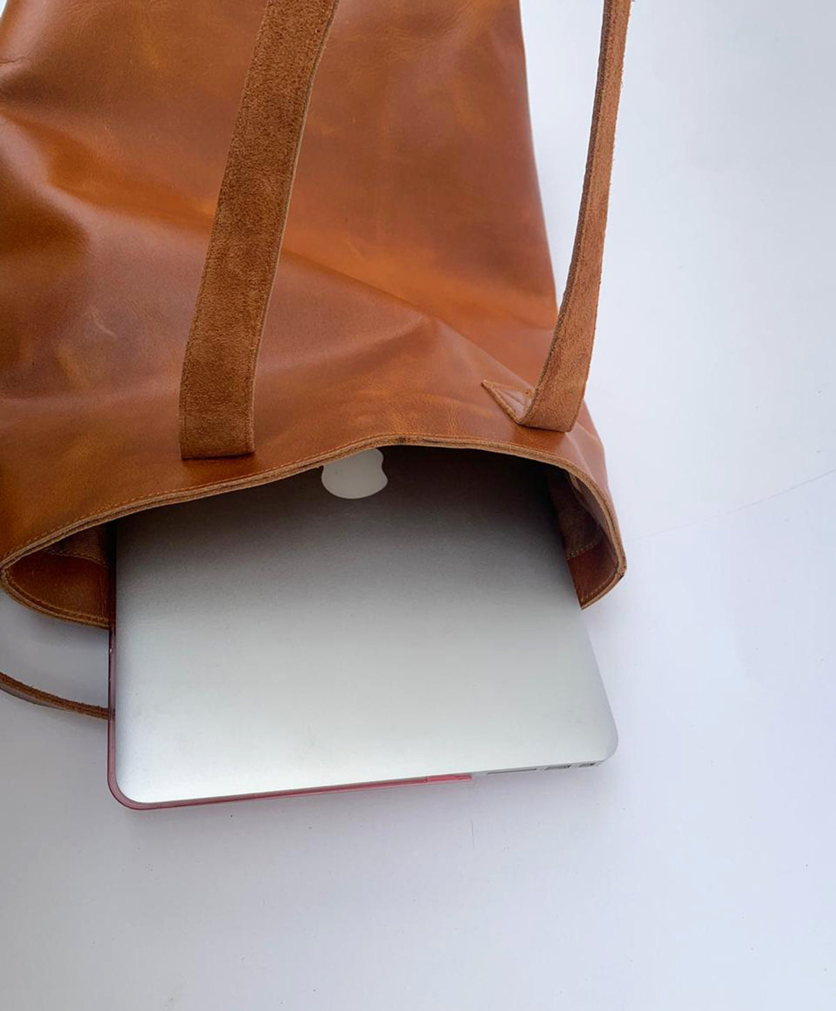 May include: A brown leather tote bag with a laptop computer inside. The bag has two long straps.