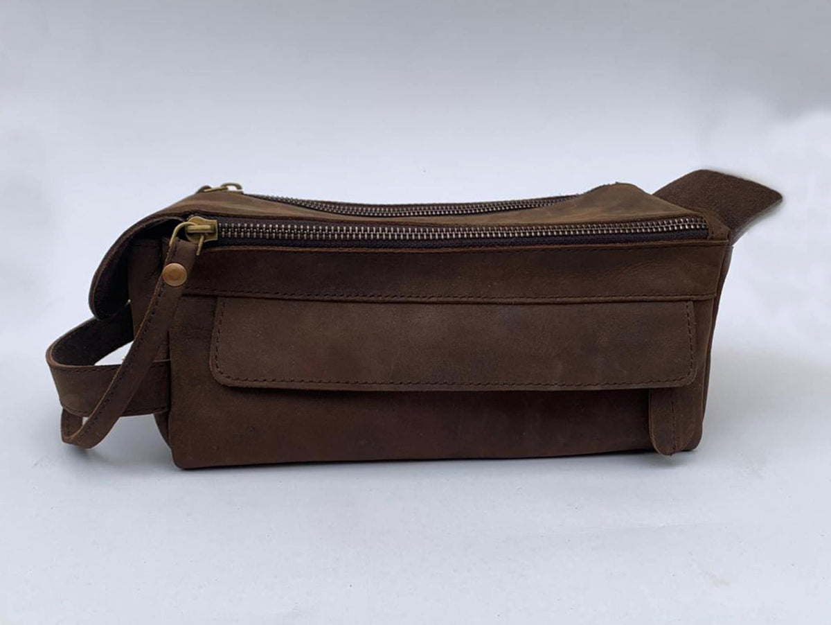 May include: A brown leather travel bag with a zipper closure and a large front pocket. The bag has a strap for carrying.