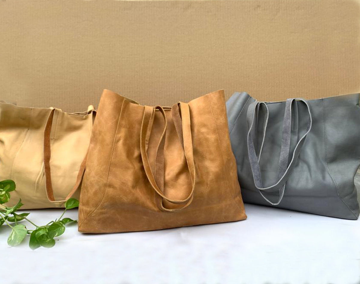 May include: Three leather tote bags in shades of tan, brown, and gray. The bags have long straps for carrying over the shoulder. The bags are made of a soft, supple leather material. The bags are empty and ready to be filled.
