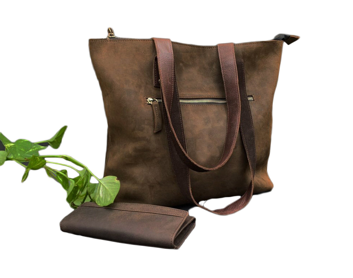 May include: A brown leather tote bag with two long straps and a smaller matching wallet. The bag has a zipper closure and a front pocket.