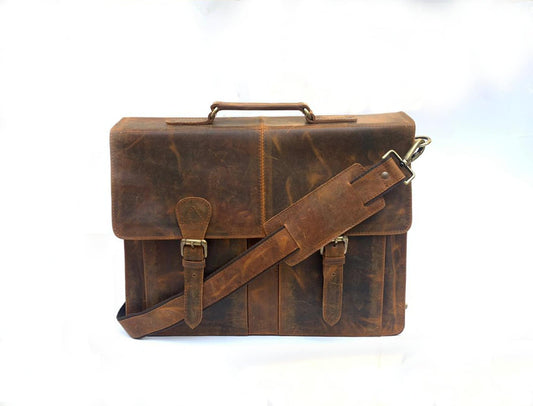 May include: A brown leather briefcase with a top handle and a detachable shoulder strap. The bag features a flap closure with two buckle straps and a distressed finish. The hardware is a brass color.