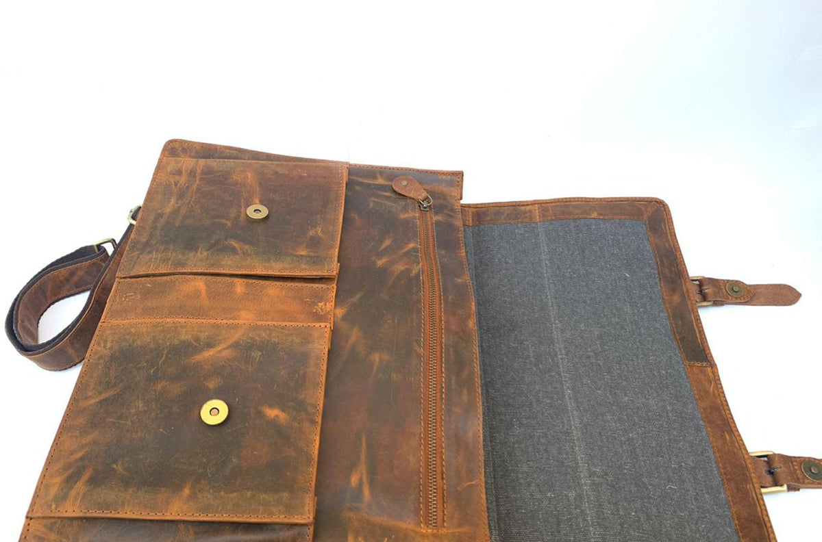 May include: A brown leather messenger bag with multiple pockets and a shoulder strap. The bag has a distressed finish, a zippered compartment, and a flap closure with a snap. The interior is lined with gray fabric.