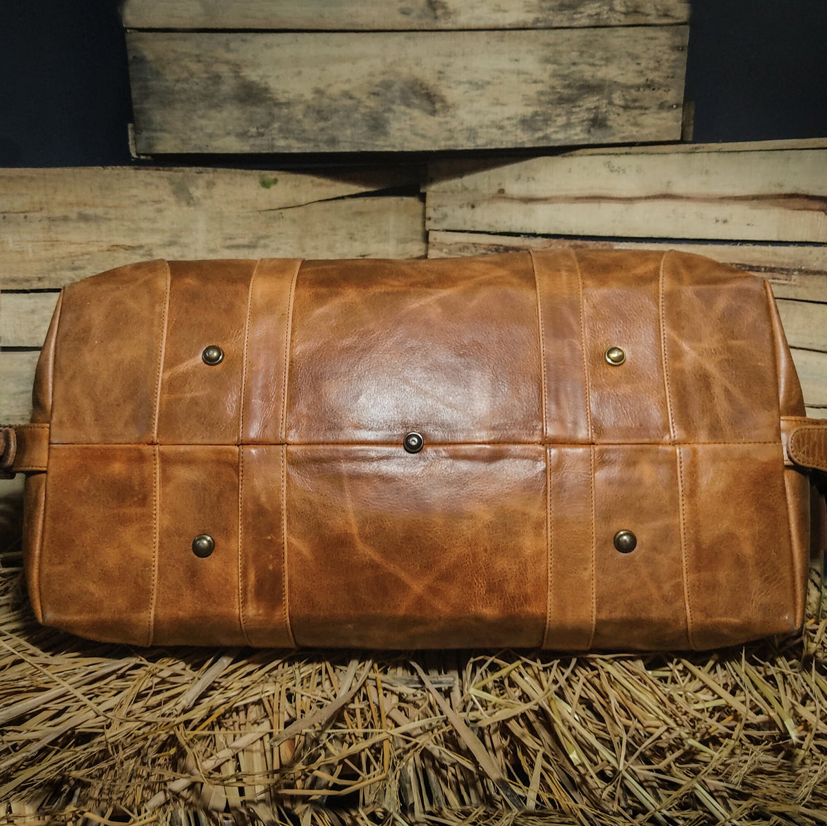 May include: A brown leather duffel bag with metal accents. The bag has a distressed look and is made of high-quality leather.