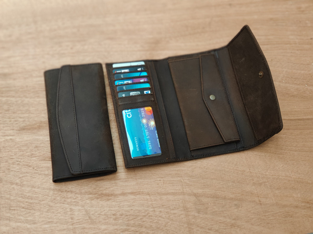 May include: A brown leather wallet with a black leather flap and a card slot. The wallet is open and has several cards inside, including a credit card with the Citi logo.