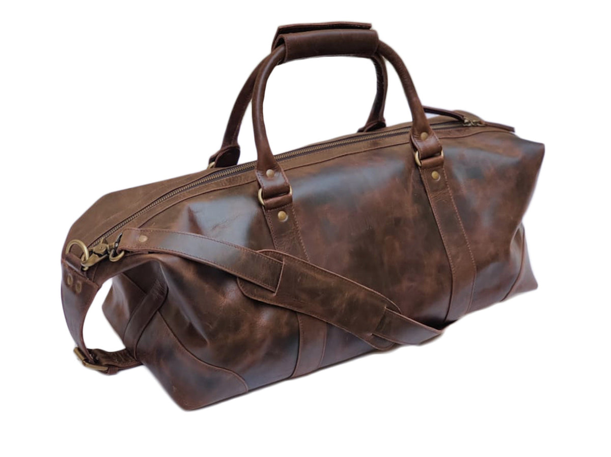 May include: A brown leather duffel bag with a top handle and a shoulder strap. The bag has a zipper closure and brass hardware.