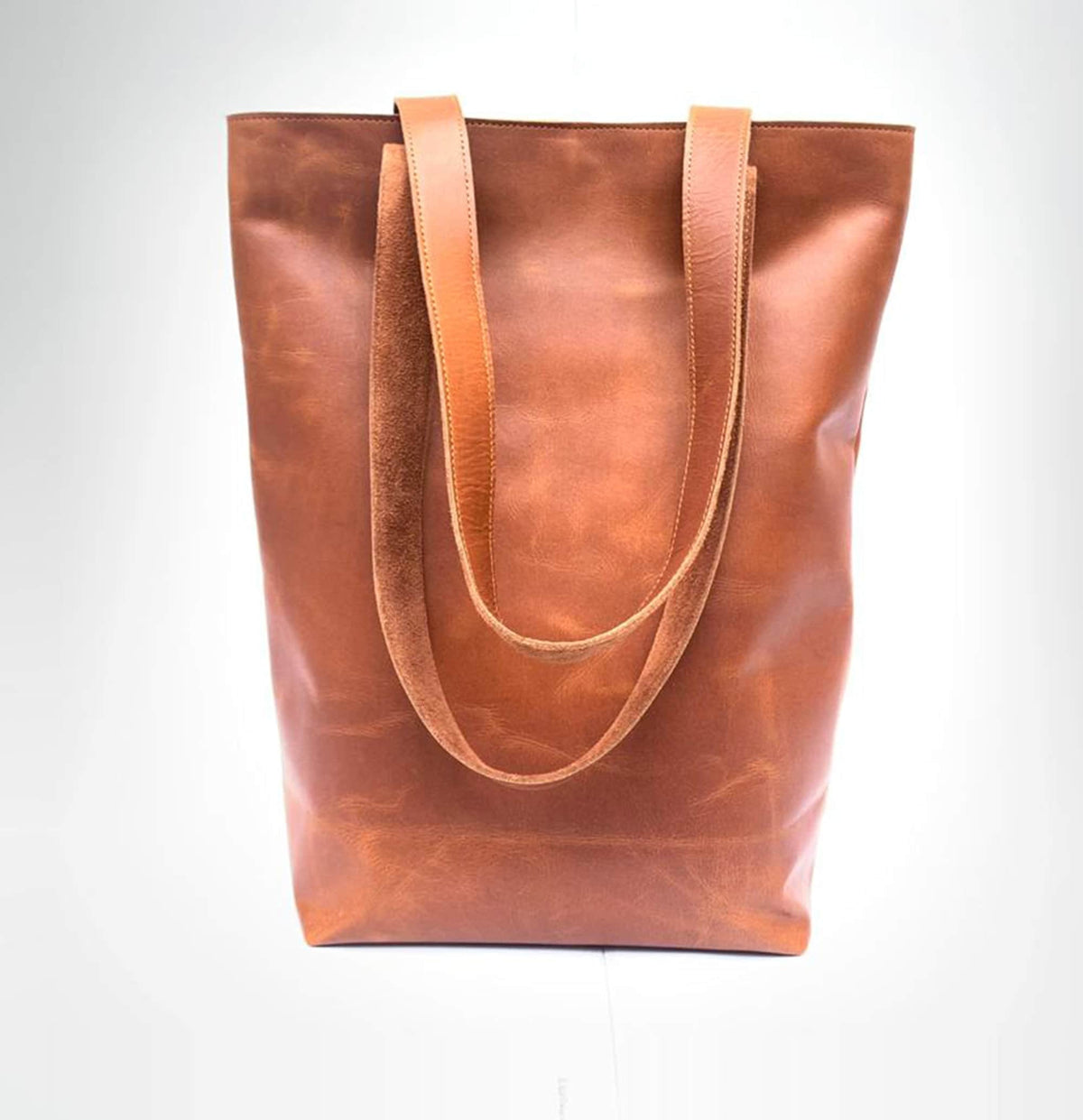 May include: A brown leather tote bag with two long straps. The bag has a slightly distressed look.
