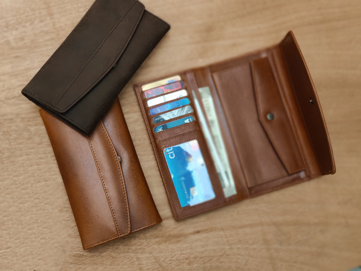 May include: Two leather wallets, one brown and one black. The brown wallet is open, showing multiple card slots and a money compartment.