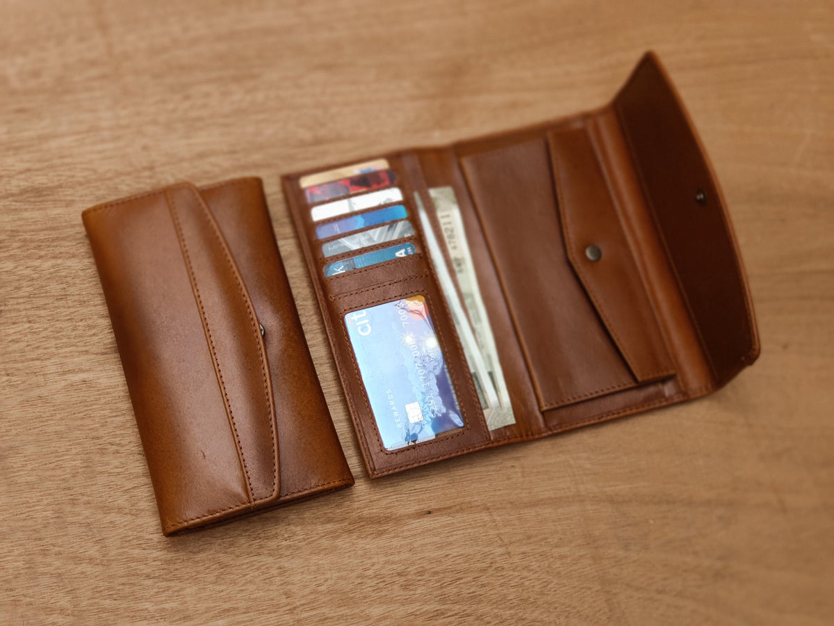 May include: A brown leather wallet with multiple card slots and a billfold. The wallet is open to reveal several credit cards and cash.