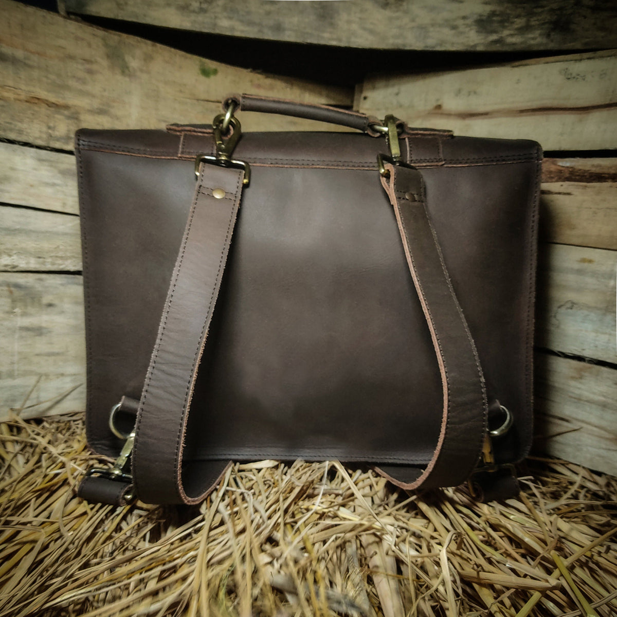 May include: A brown leather backpack with adjustable straps and brass hardware. The backpack has a flap closure and a top handle.