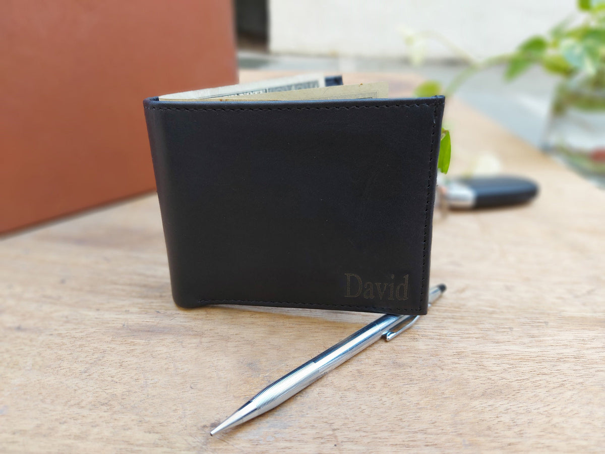 May include: A black leather wallet with the name "David" embossed in gold lettering. The wallet is open and has a few bills inside.