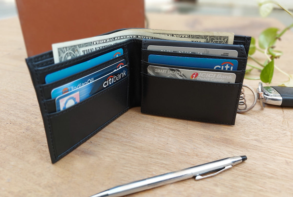 May include: A black leather wallet with a key chain attached. The wallet is open and contains several credit cards, including a Citibank card, an ICICI Bank Debit Card, and a Smart Shopper card. There is also a dollar bill inside the wallet.