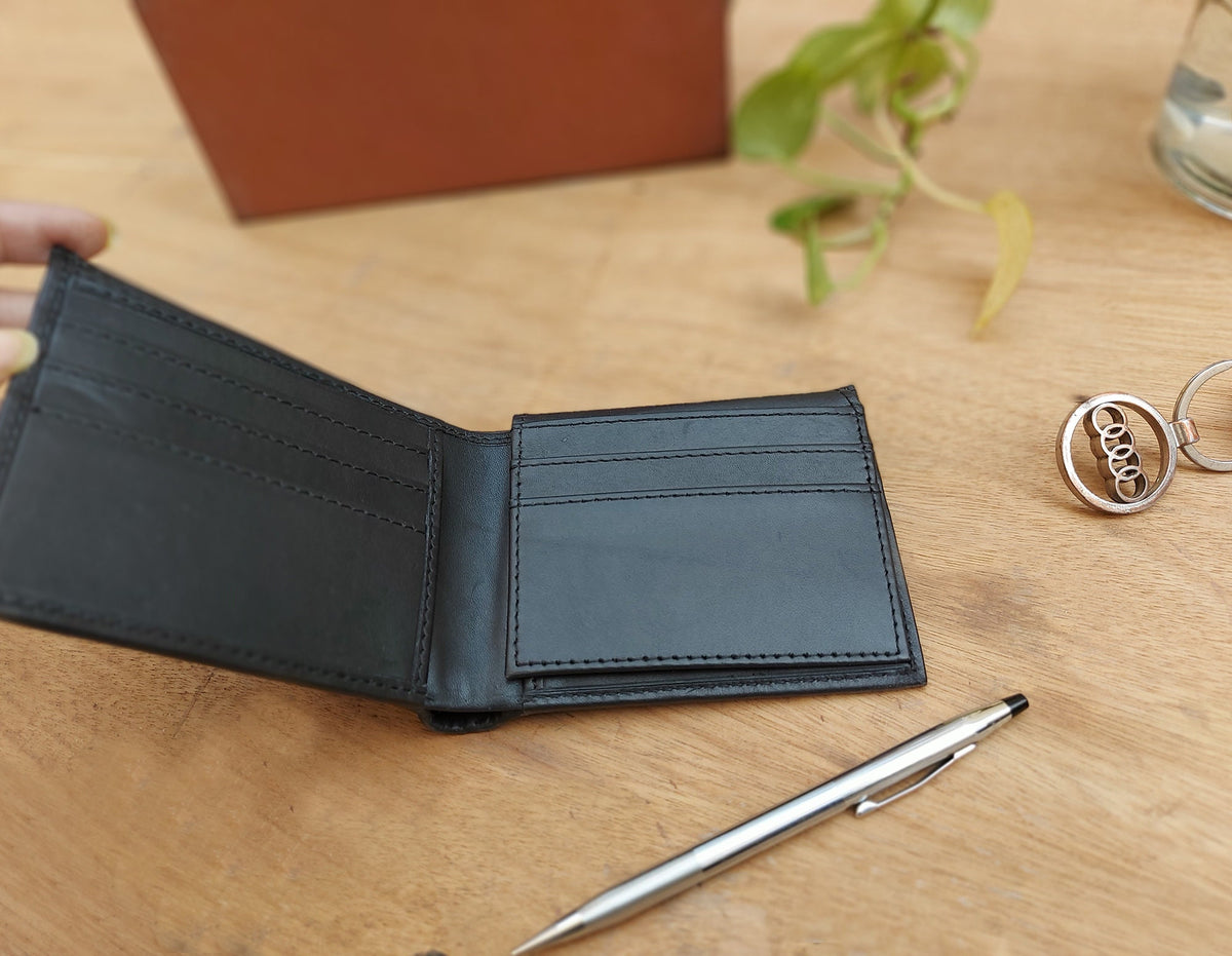May include: A black leather wallet with multiple card slots and a billfold. The wallet is open and lying on a wooden surface.