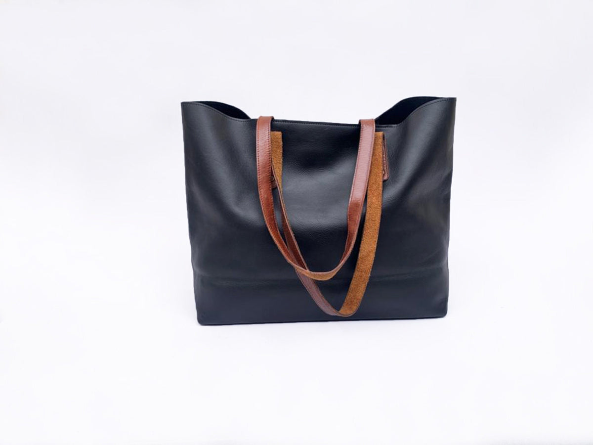 May include: A black leather tote bag with brown leather straps. The bag has a simple design and is perfect for everyday use.