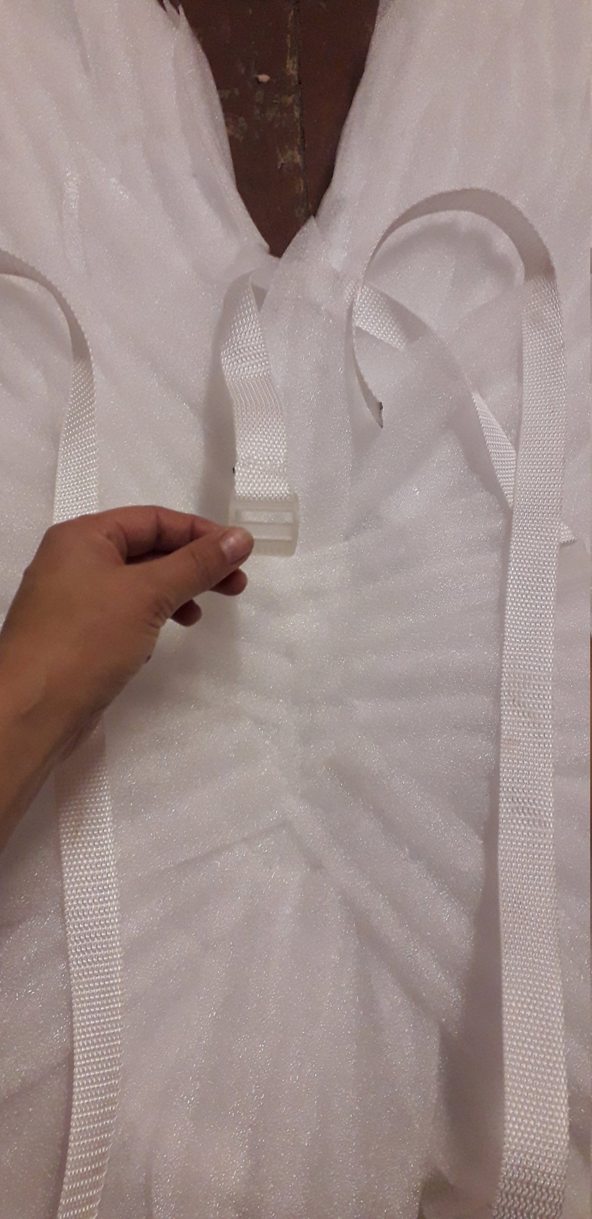 May include: White fabric with two white straps and a white plastic buckle.