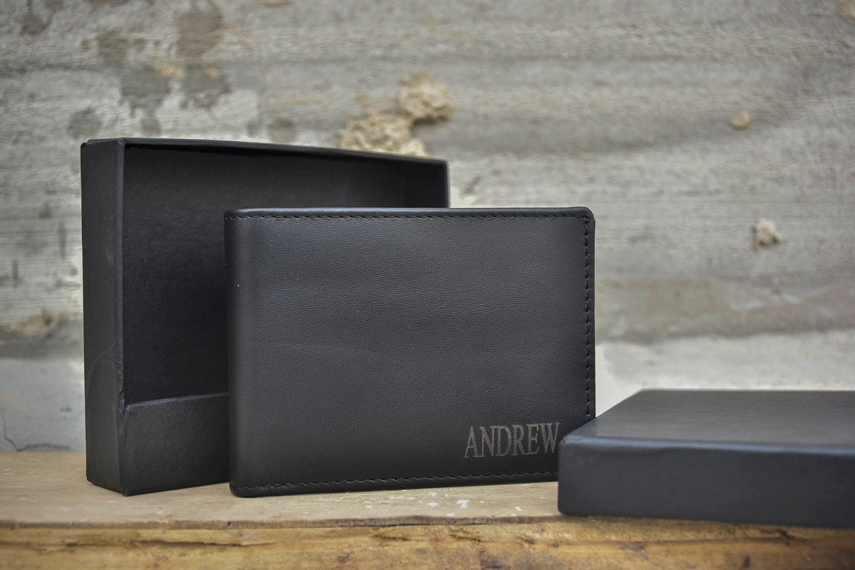 May include: A black leather wallet with the name "ANDREW" engraved on the front. The wallet is in a black box.