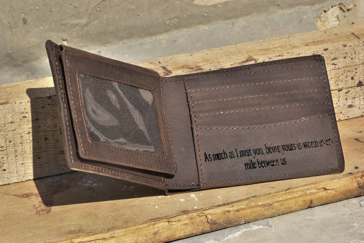 May include: A brown leather wallet with a clear plastic window for a photo ID. The wallet has a personalized inscription that reads: "As much as I miss you, being yours is worth every mile between us."