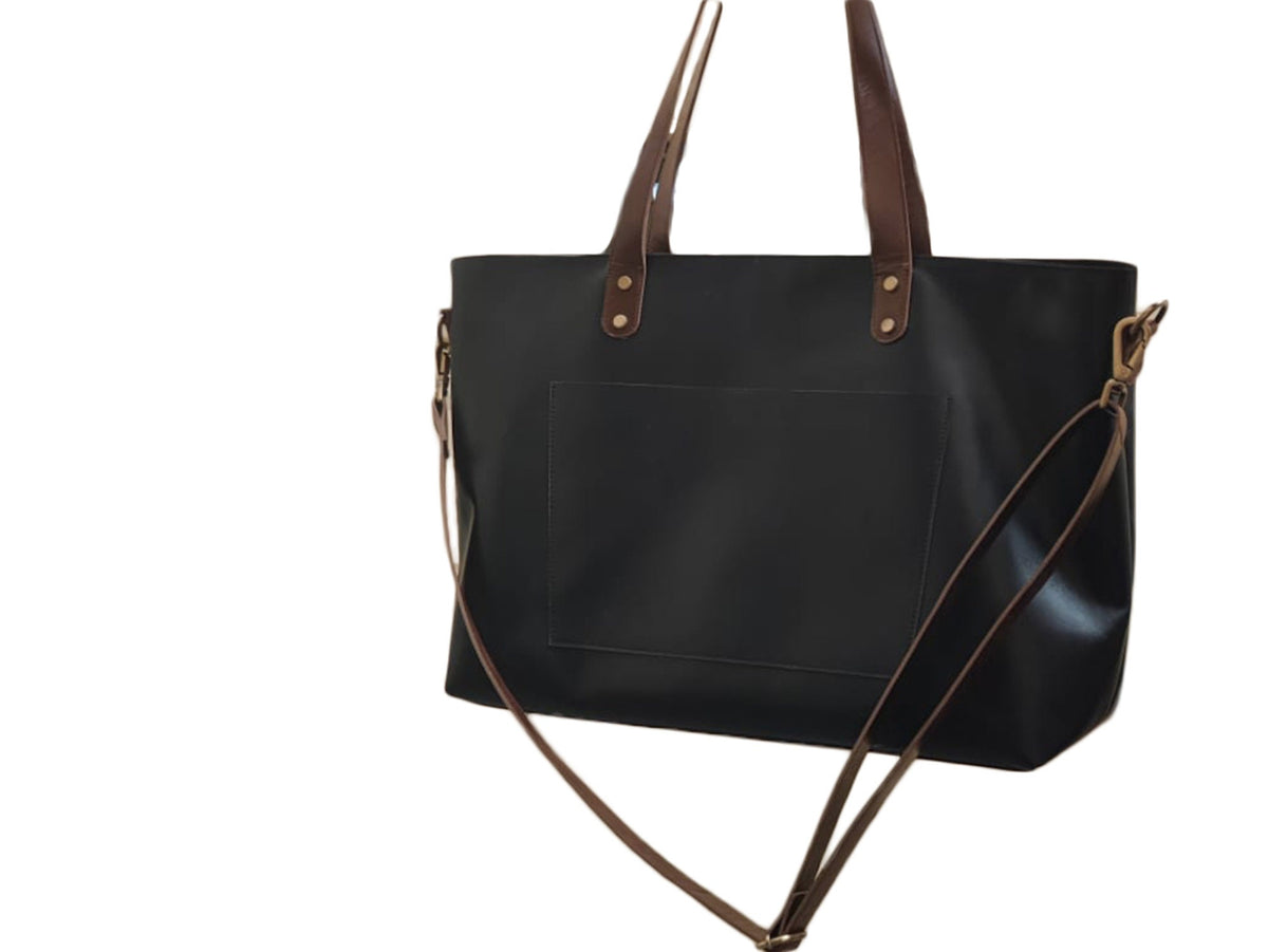 May include: Black leather tote bag with brown leather handles and a long brown leather strap. The bag has a front pocket and gold-colored hardware.