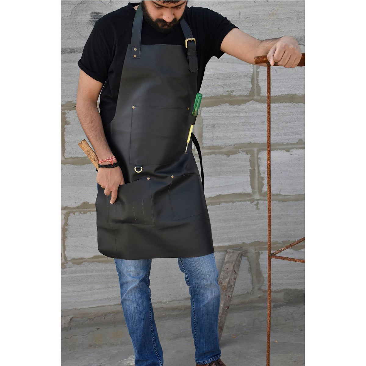 May include: A black leather apron with a large pocket and a tool loop. The apron has a brass buckle and adjustable straps.