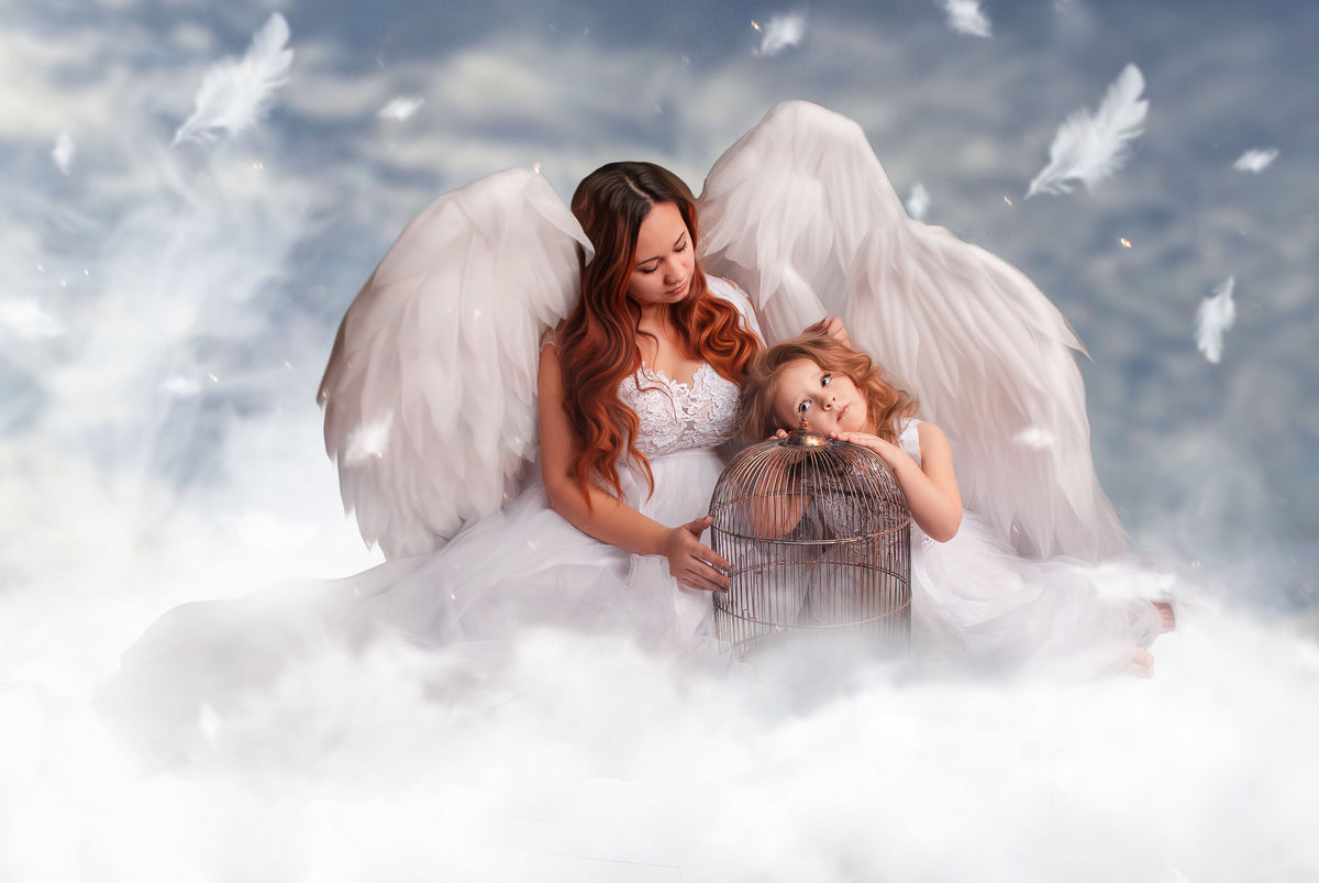 May include: A mother and child dressed in white angel costumes with large white feathered wings. They are seated on a cloud, with feathers floating in the sky. The child is leaning on a birdcage.