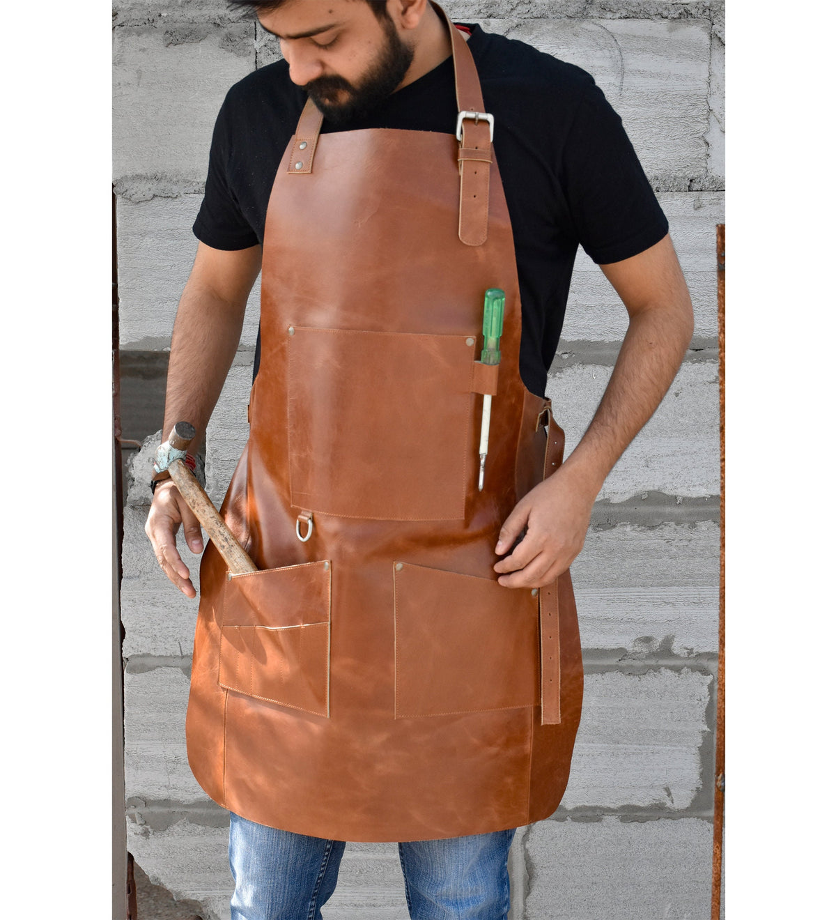 May include: A brown leather apron with multiple pockets and a tool holder. The apron has adjustable straps and a metal buckle.