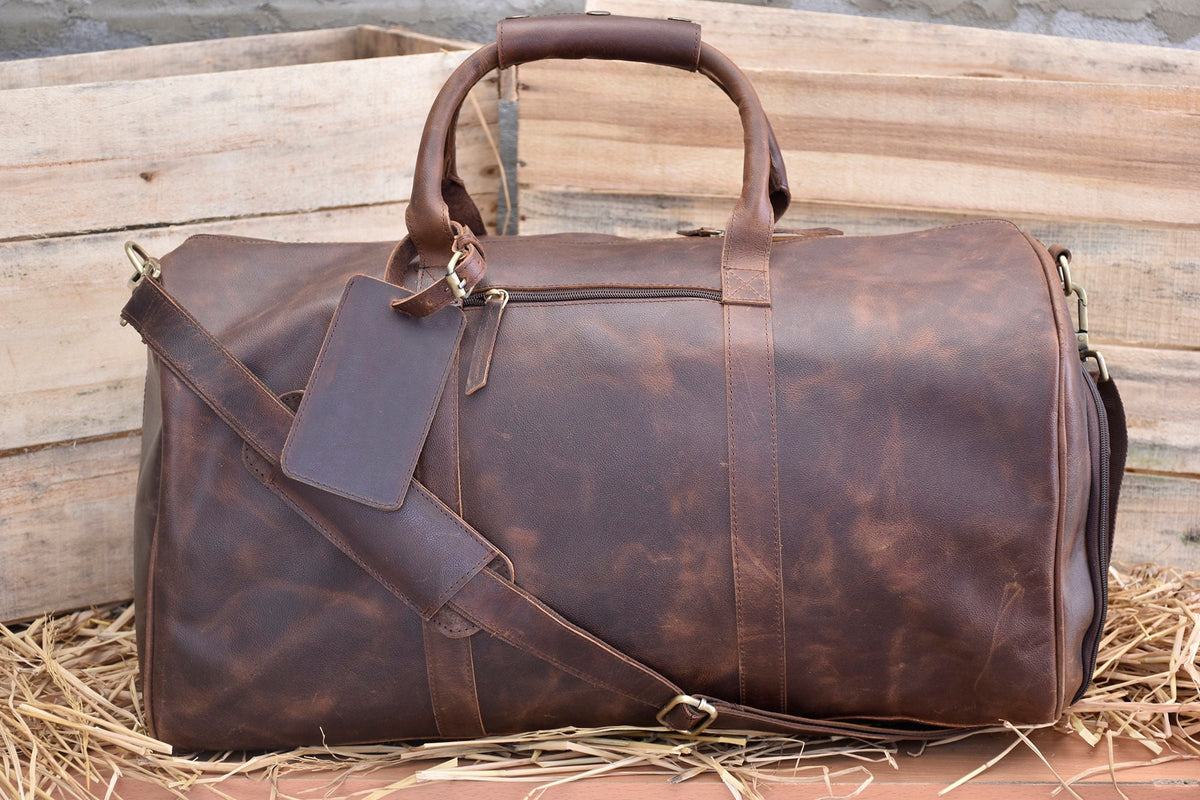 May include: A brown leather duffel bag with a shoulder strap and a luggage tag. The bag has a zipper closure and a top handle.