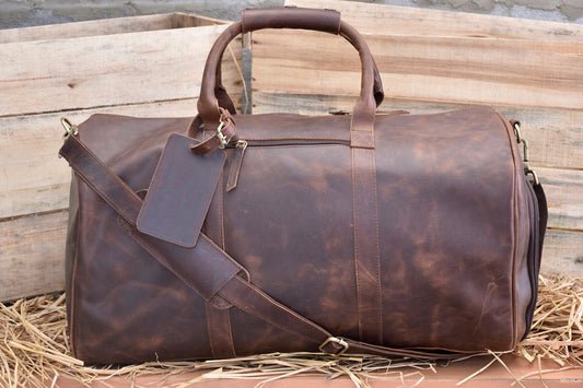 May include: A brown leather duffel bag with a shoulder strap and a luggage tag. The bag has a zipper closure and a top handle.