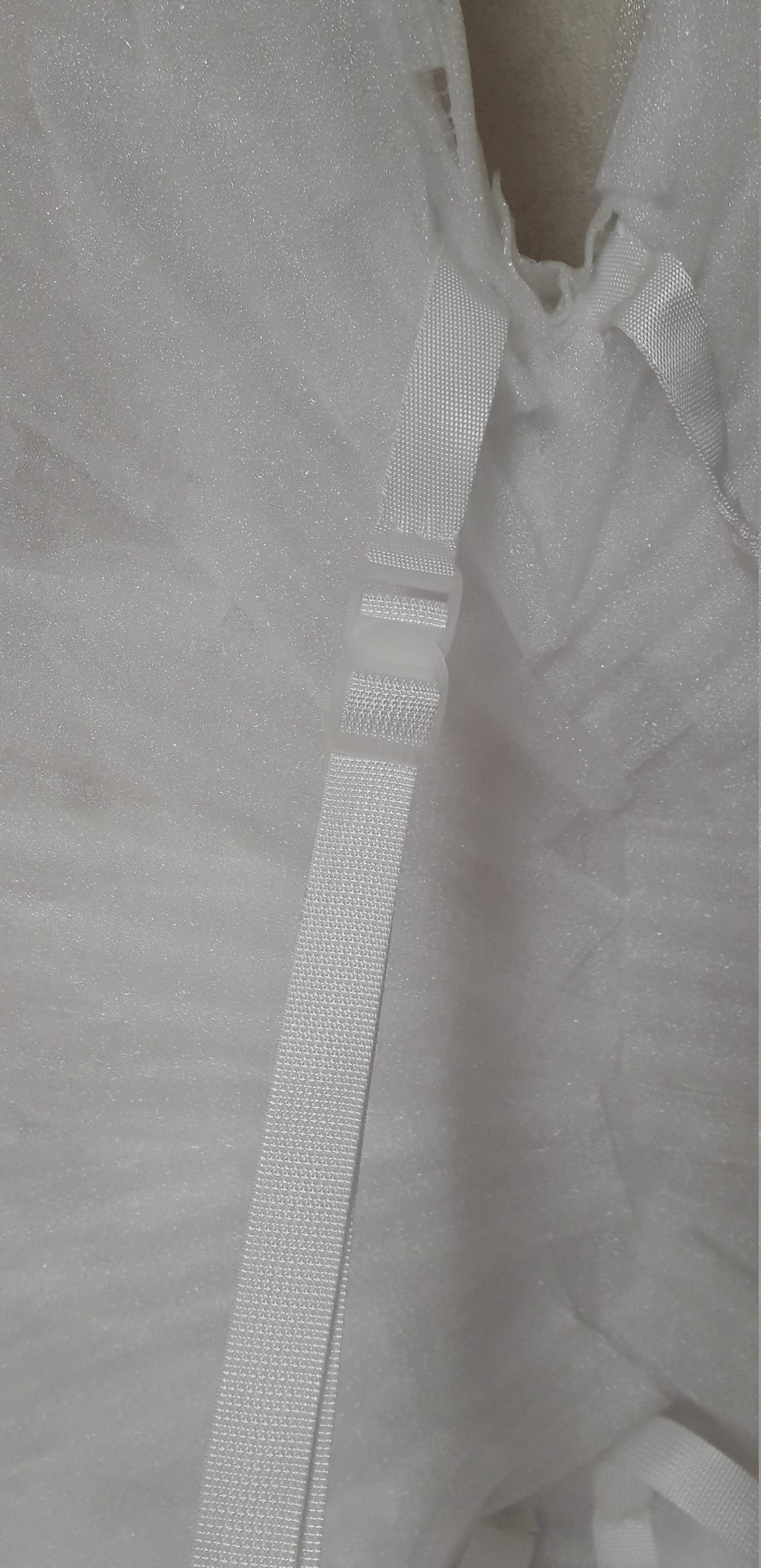 May include: White adjustable straps with a plastic buckle. The straps are made of a woven material.