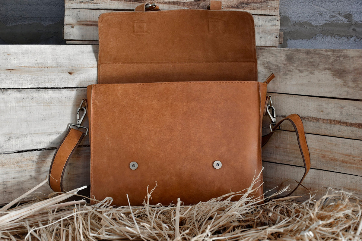 May include: A brown leather messenger bag with a flap closure and a long adjustable strap. The bag is open and the inside is visible.