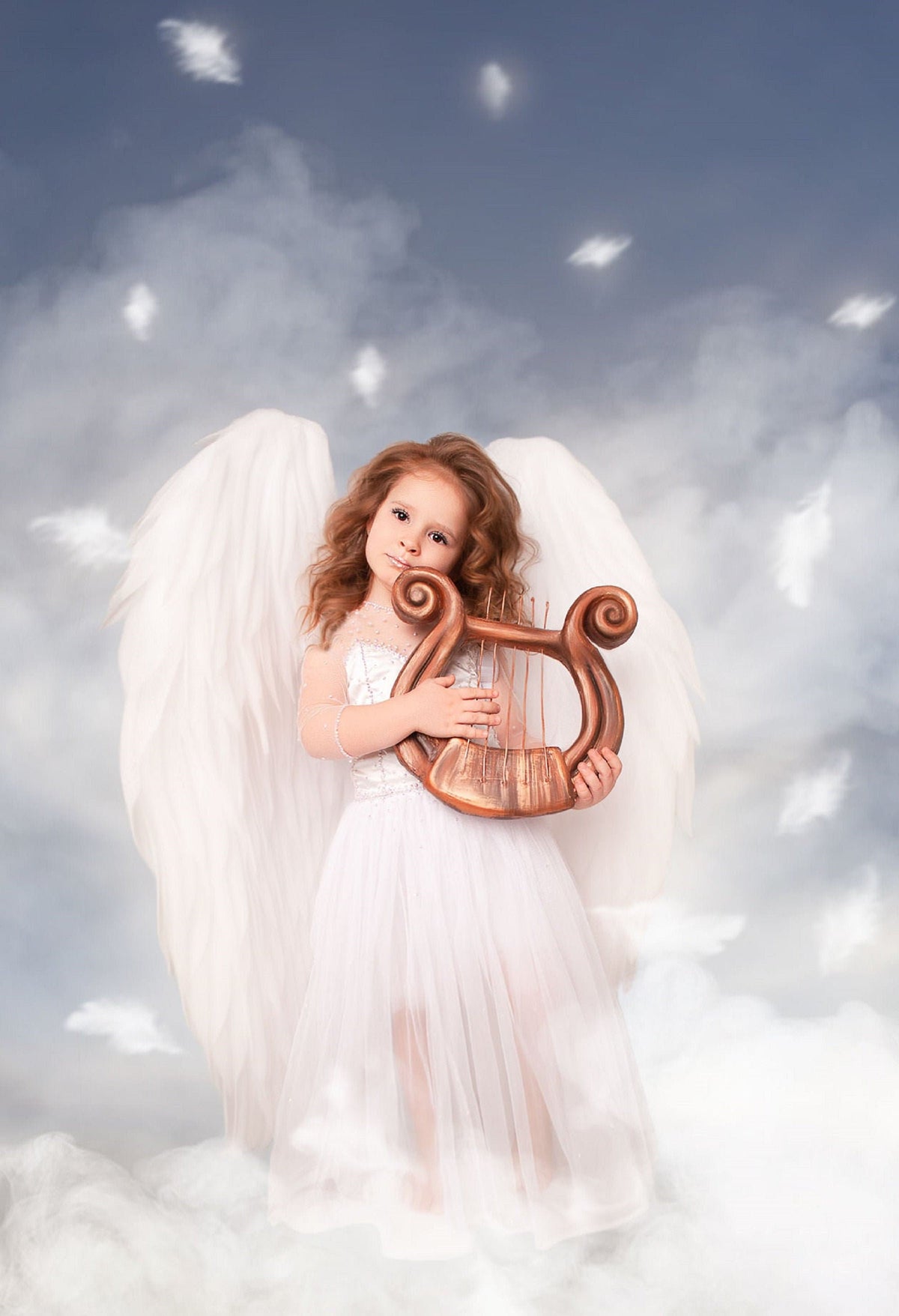 May include: A young girl dressed as an angel with white wings and a white dress holds a brown lyre in front of a cloudy blue background.