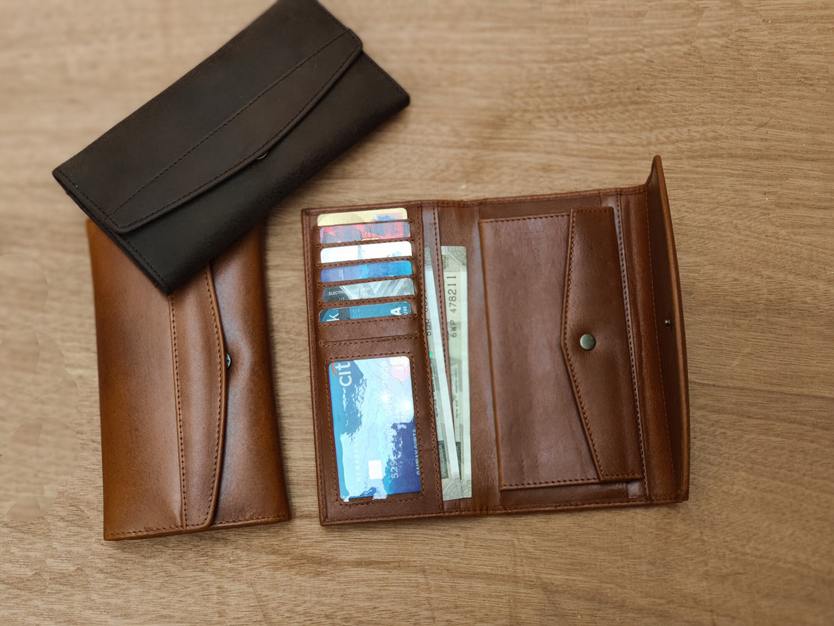 May include: Two leather wallets, one brown and one black, are open and laid out on a wooden surface. The brown wallet has multiple card slots and a billfold, while the black wallet has a more simple design.