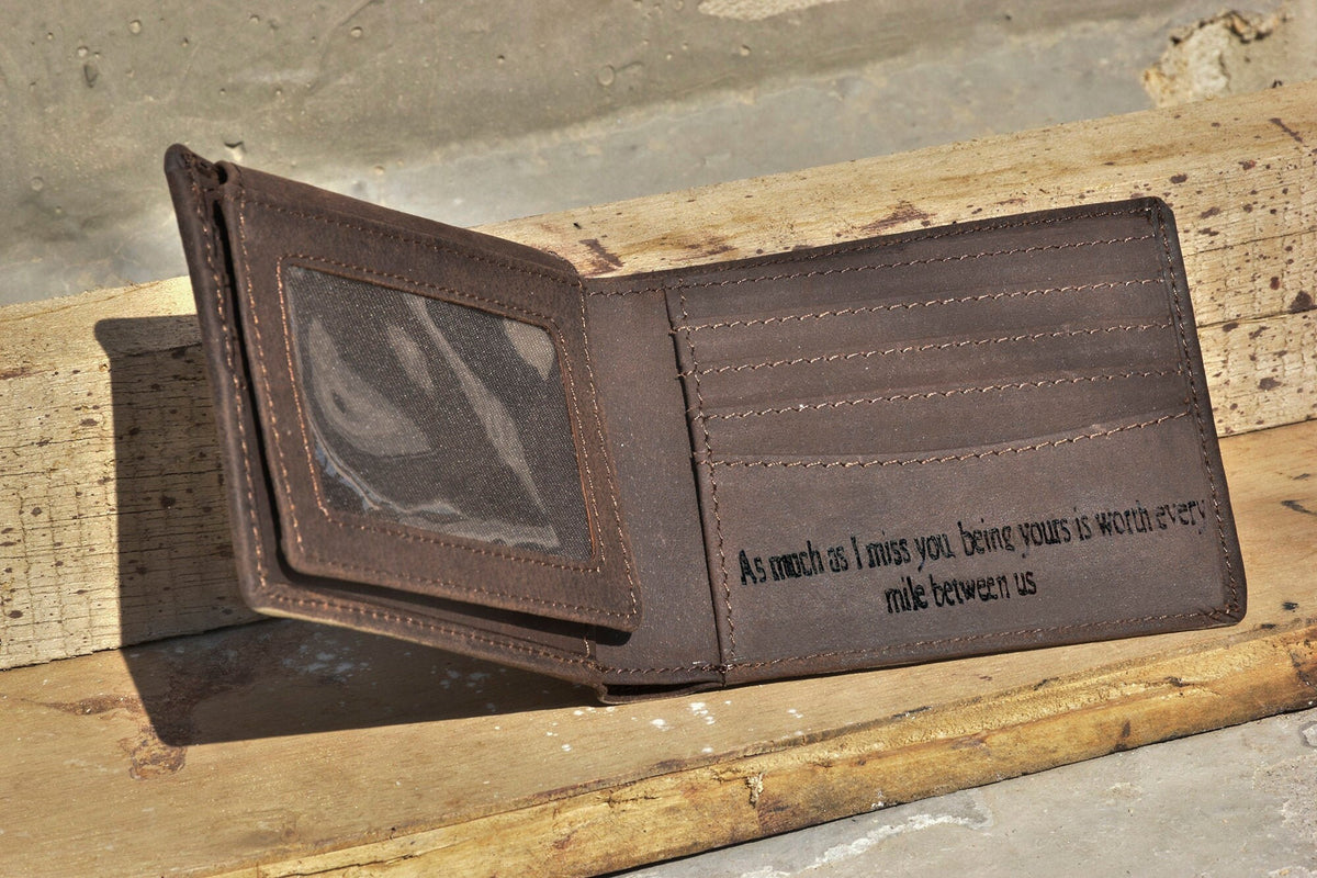 May include: A brown leather wallet with a clear plastic window for a photo ID. The wallet has a personalized inscription that reads "As much as I miss you, being yours is worth every mile between us."