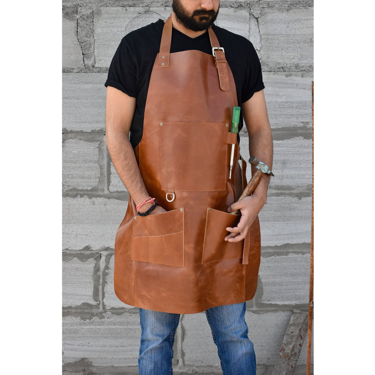May include: A brown leather apron with multiple pockets and a tool loop. The apron has a strap that goes around the neck and another strap that goes around the waist.