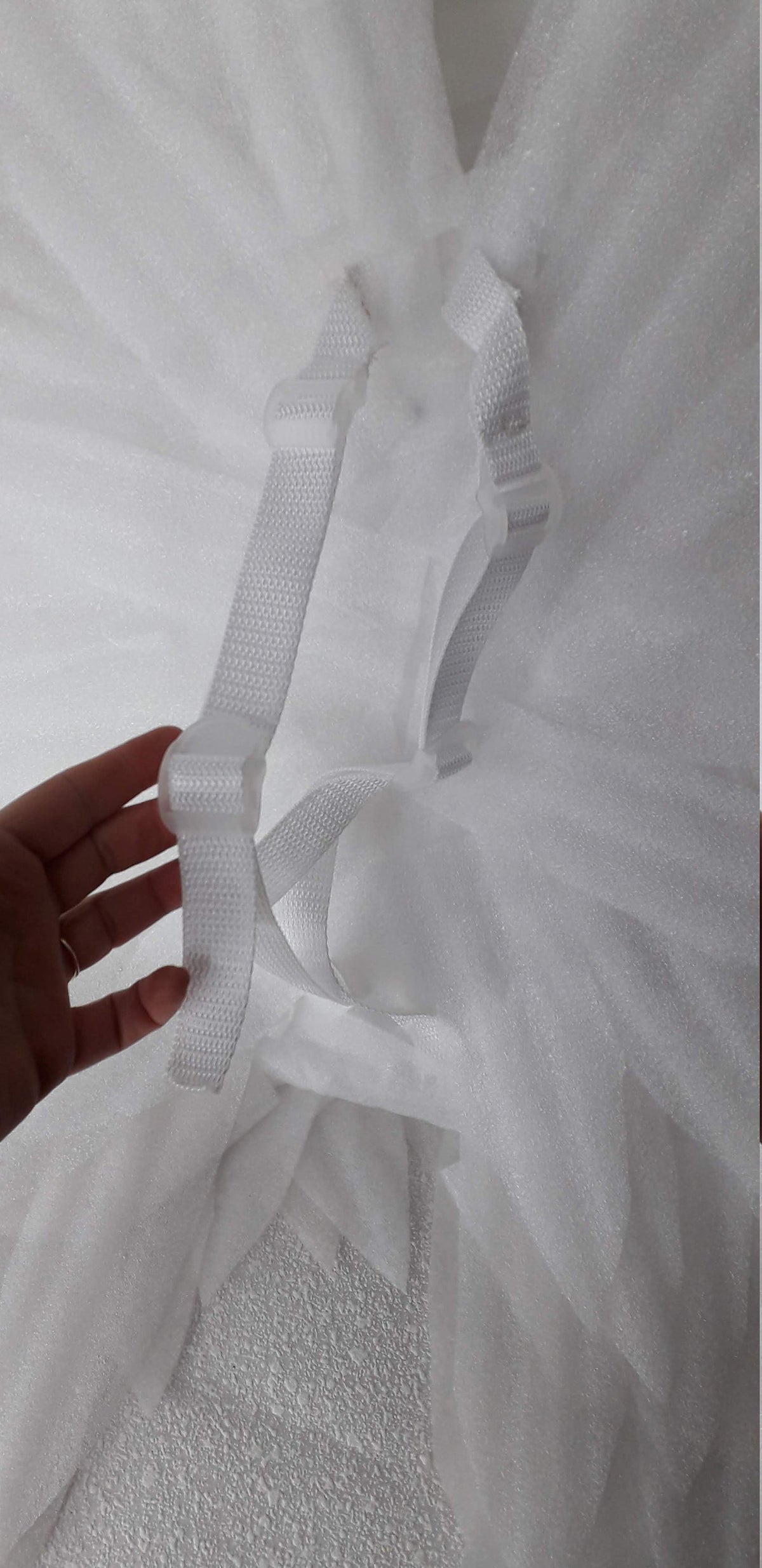 May include: White tulle tutu skirt with white adjustable straps. The straps are made of a woven nylon material and have a hook and loop closure.