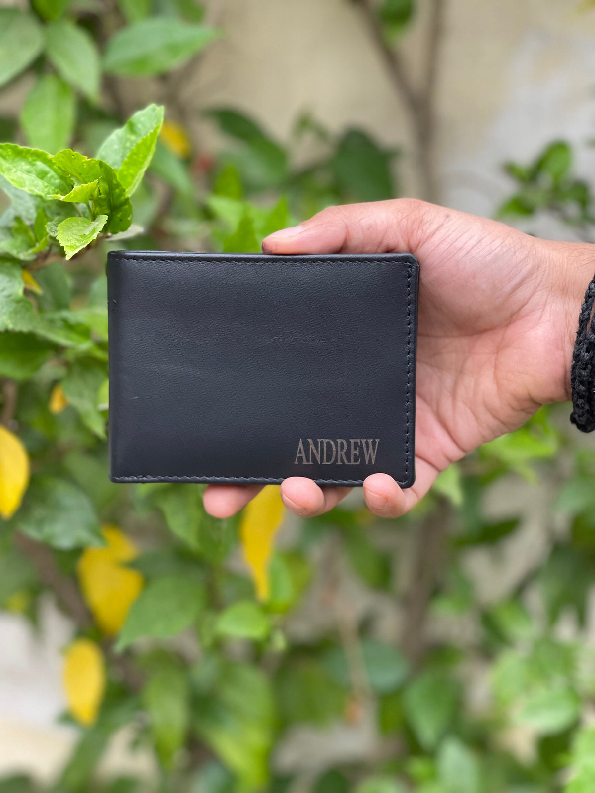 May include: A black leather wallet with the name "ANDREW" embossed in gold lettering.
