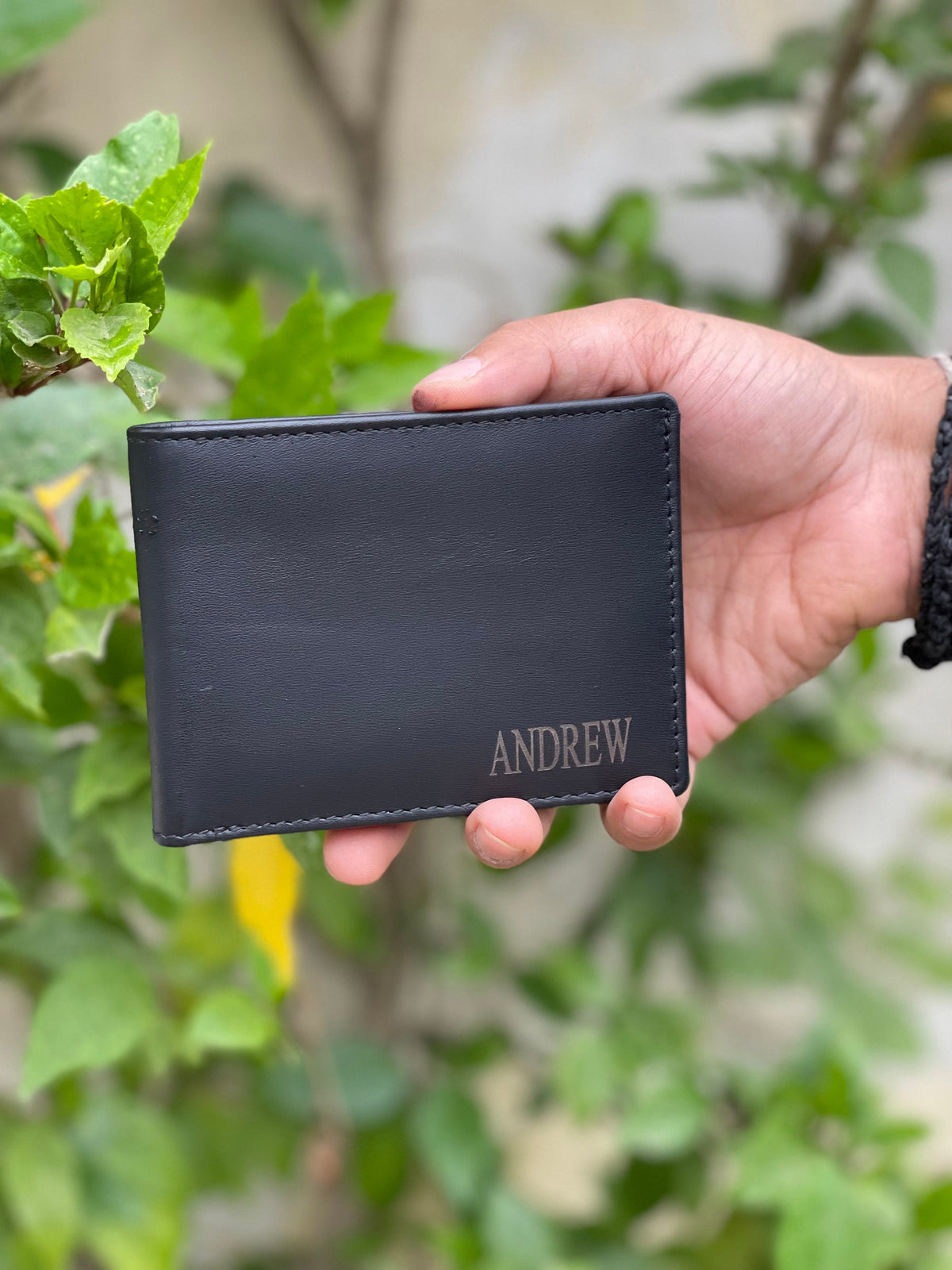 May include: A black leather wallet with the name "ANDREW" embossed in silver lettering.