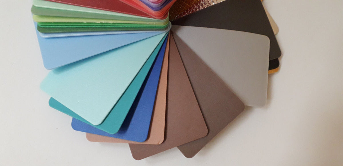 May include: A color chart with a variety of shades, including light blue, teal, green, brown, gray, and black. The chart is fanned out in a circle.