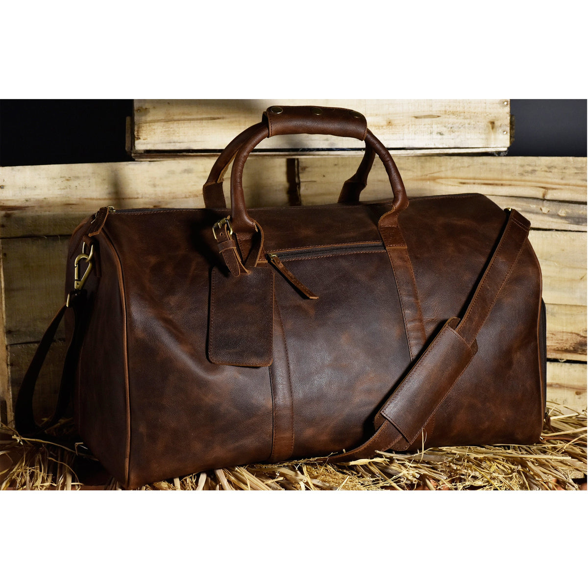 May include: A brown leather duffel bag with a top handle and a shoulder strap. The bag has a zipper closure and a small pocket on the front.