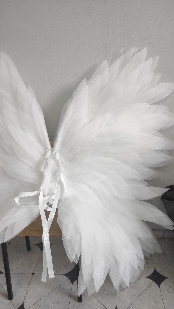 May include: White tulle angel wings with a tie closure. The wings are layered and have a feathery appearance.