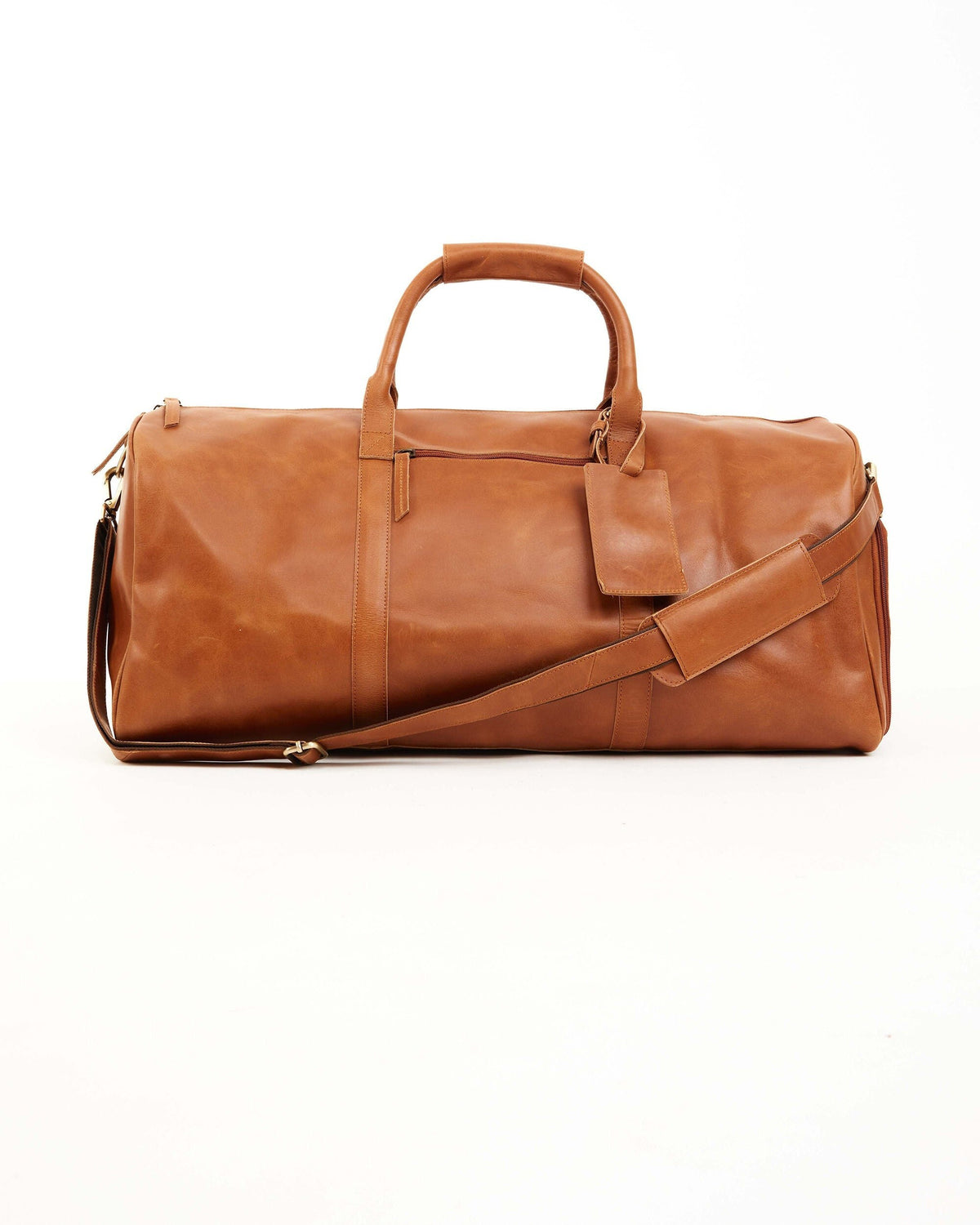 May include: A brown leather duffel bag with a top handle and a detachable shoulder strap. The bag has a rectangular shape with a zipper closure and a small tag attached. The bag is designed for travel and has a classic, timeless look.