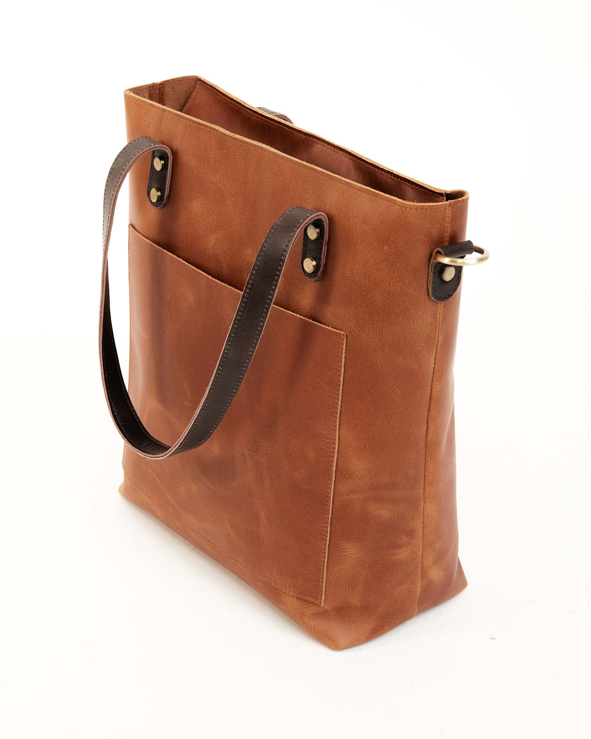 May include: A brown leather tote bag with a dark brown leather strap and a front pocket. The bag has a gold metal ring on the strap.