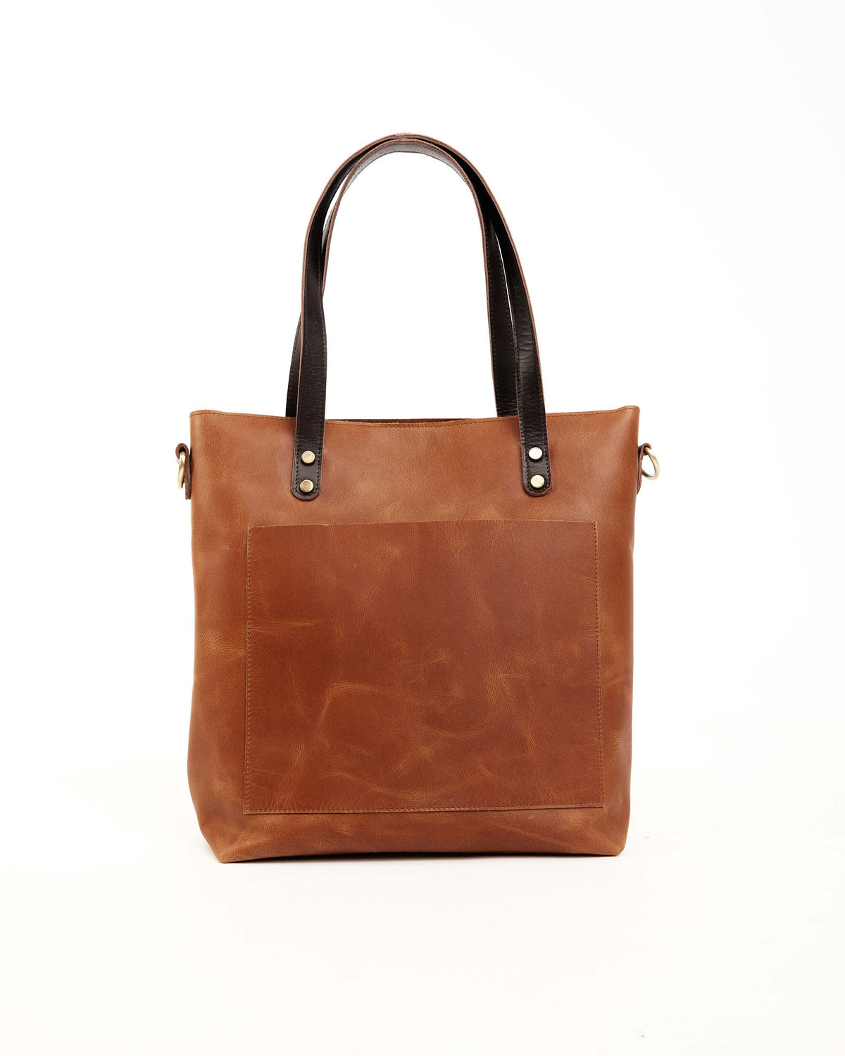 May include: A brown leather tote bag with a brown leather strap and a front pocket. The bag has a dark brown trim and gold-colored hardware.