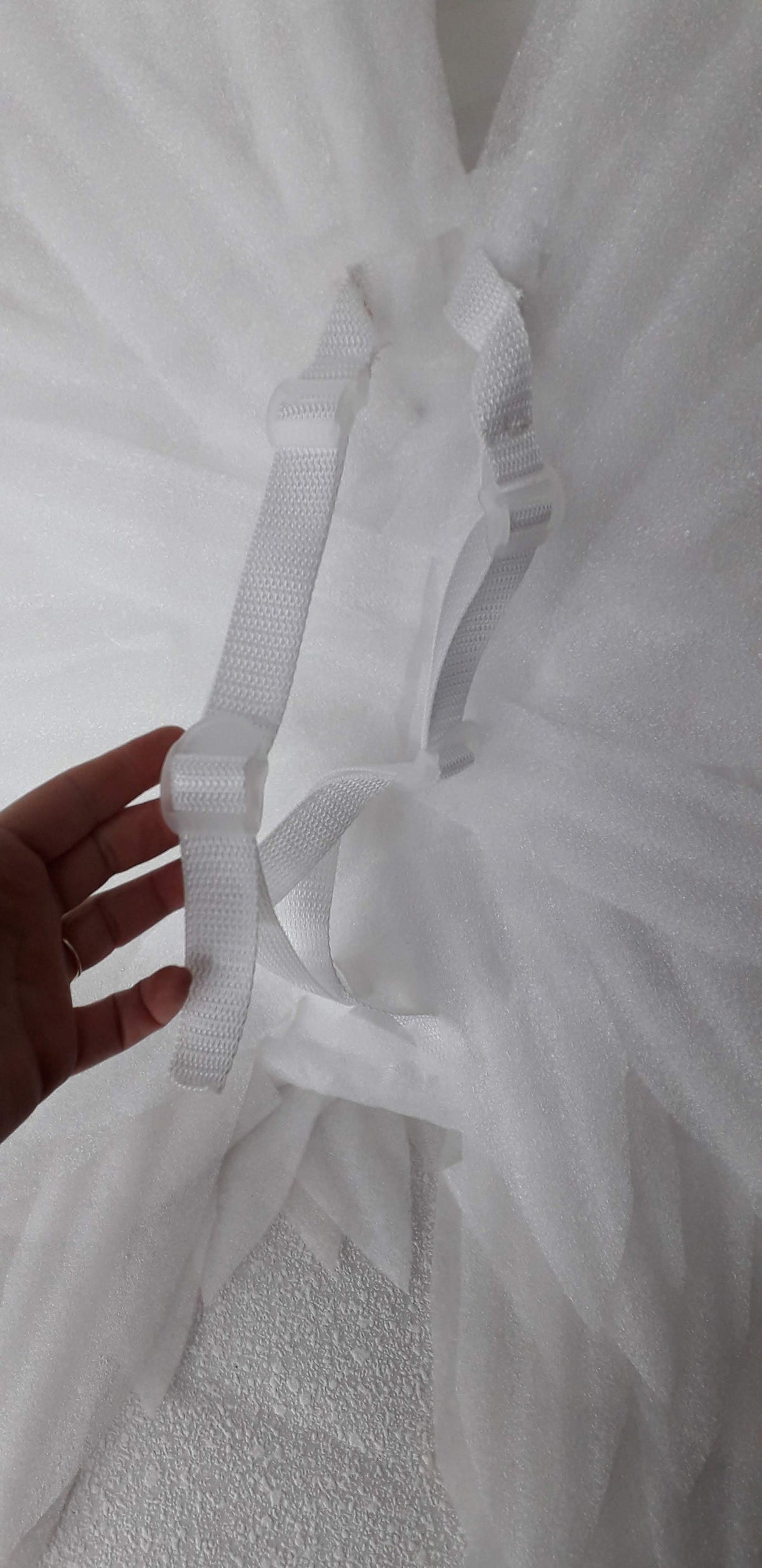May include: White tulle fabric with two white adjustable straps with plastic buckles. The straps are sewn to the fabric and can be adjusted to fit.
