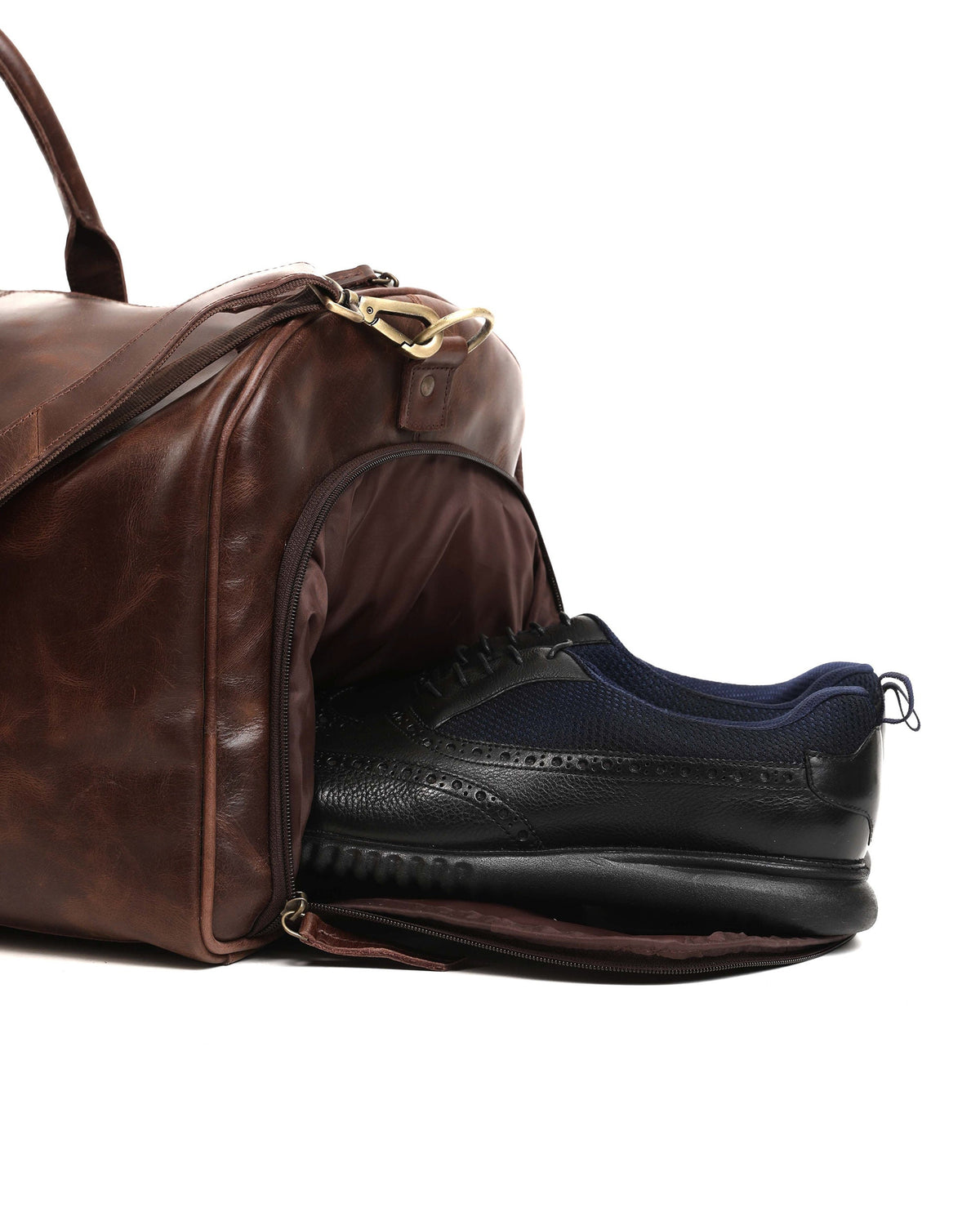 May include: A brown leather duffel bag with a black shoe inside. The bag has a shoulder strap and a zipper closure. The shoe is black with a blue mesh upper and a thick black sole.