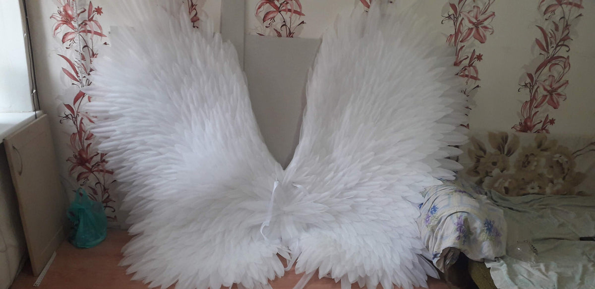 May include: A pair of large, white angel wings made of feathers. The wings are spread out and appear to be made of soft, fluffy feathers.