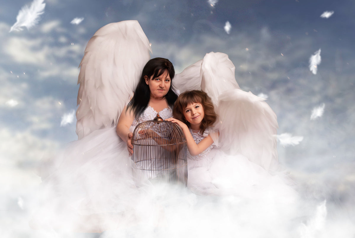 May include: A woman and a child dressed in white angel costumes with large white feathered wings. They are holding a decorative birdcage. The background is a cloudy sky with falling feathers.
