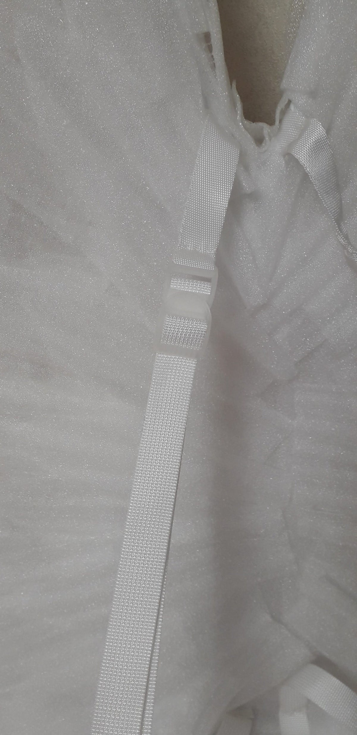 May include: White adjustable straps with a plastic buckle. The straps are made of a woven material.