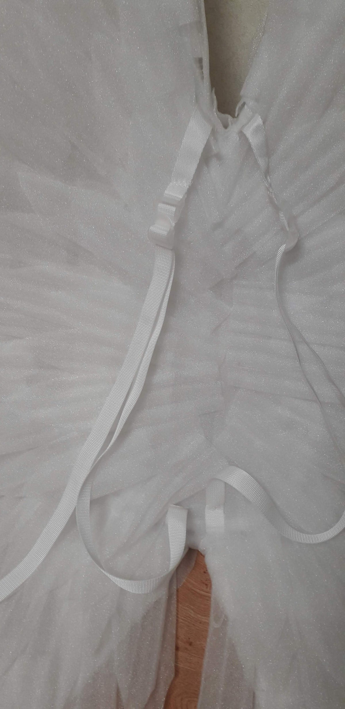 May include: White tulle wings with white straps and adjustable buckles. The wings are made of a soft, sparkly material.